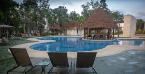 einen Pool mit Stühlen und einem Pavillon in der Unterkunft Casa Tucan. A contemporary holiday or work nest in Puerto Morelos
