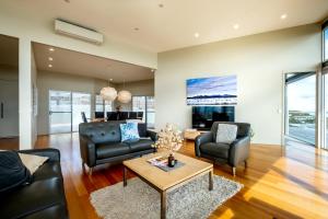 a living room with couches and a table at Halcyon ~ Immerse yourself in the sky and sea in Coles Bay