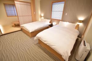 a hotel room with two beds and two windows at K-style Higashihonganji in Shimmachidōri