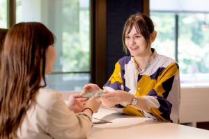 a woman sitting at a table talking to another woman at Yamanakaonsen Ohanami Kyubei in Kaga