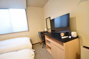 um quarto de hotel com uma televisão de ecrã plano e uma cama em K-style Higashihonganji em Shimmachidōri