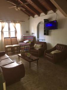 sala de estar con sofás de cuero y TV en El Parralito en Luján de Cuyo