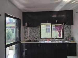 a kitchen with black cabinets and a sink and a window at Island Guesthouse - entire one bedroom unit with kitchen & a bathroom centrally located in Votualevu in Nadi