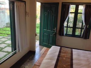 a bedroom with a green door and a window at Tam Coc Eco House in Ninh Binh