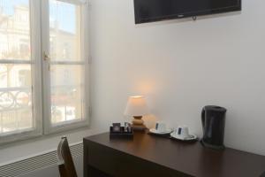 a desk with a lamp sitting on it next to a window at Hôtel Restaurant Le Lion d'Or in Gémozac