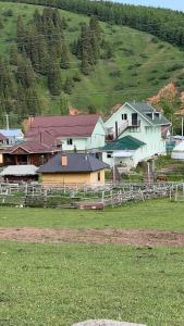 a group of buildings in a field next to a hill at Alakol-Jyrgalan Guest House in Dzhergalan