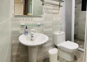 a white bathroom with a toilet and a sink at Good Days in Yuli
