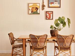 a dining room table with three chairs and a plant at Atlantic Byron Bay in Byron Bay