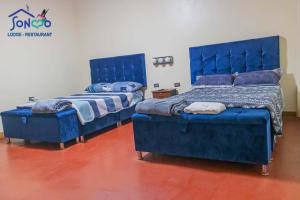 two beds in a room with blue furniture at SONCCO LODGE-RESTAURANT in Quillabamba