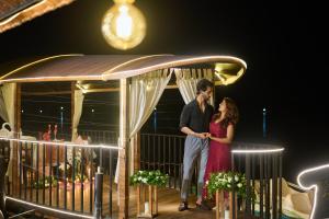 a man and a woman standing on a deck at night at Maliekal Heritance Cherai Beach Cochin in Cherai Beach