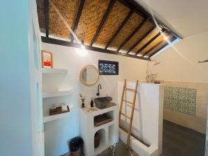 a bathroom with a sink and a mirror at Adi's Bungalow in Uluwatu