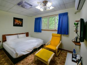 a bedroom with a bed and a yellow chair at Nantou Fruit House in Renai