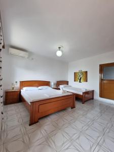 two beds in a large room with white walls at Lida's House in Lukovë