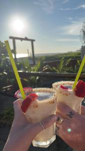 two hands holding two drinks with strawberries in them at Un Dia Boutique Resort in Playas