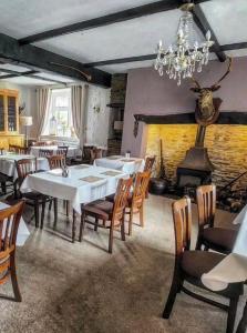 uma sala de jantar com mesas e cadeiras e uma lareira em The Royal Oak Inn em Withypool