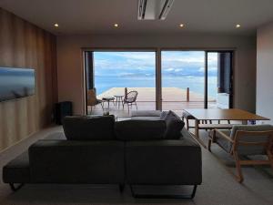 ein Wohnzimmer mit einem Sofa und Meerblick in der Unterkunft SETO CLAS AJI THE SEASIDE HILLS RESORT in Aji