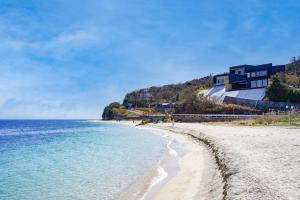 a beach with a house on a hill next to the water at SETO CLAS AJI THE SEASIDE HILLS RESORT in Aji