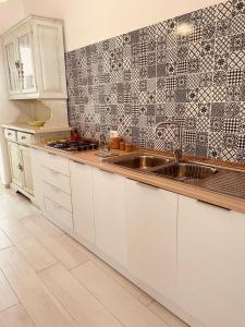 a kitchen with a sink and a tile wall at Villino Dodò in Torre San Giovanni Ugento