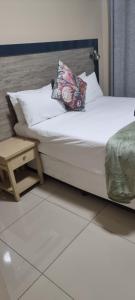 a bed with white sheets and a pillow and a table at Awethu Guest House in Richards Bay