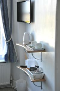 a shelf with dishes and a tv on a wall at Gordon House B & B in Tintagel