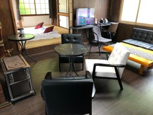 Sala de estar con cama, mesas y sillas en Cool-Cottage Otaru OTAMOI, en Otaru