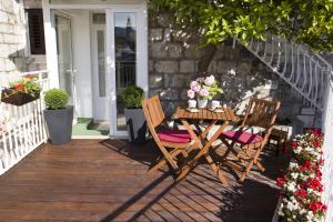 einen Holztisch und Stühle auf einer Veranda mit Blumen in der Unterkunft Studio apartment Malo more in Trogir