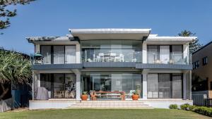 a large house with glass windows and a patio at Beachside Lennox in Lennox Head