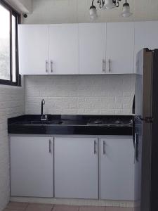 uma cozinha com armários brancos, um lavatório e um frigorífico em Encantador y Confortable Apartamento em Neiva