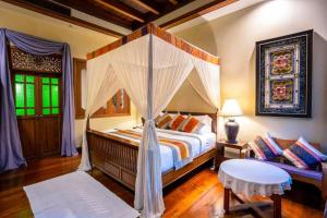 1 dormitorio con cama con dosel y sofá en Amata Lanna Village อมตะล้านนาวิลเลจ en Chiang Mai