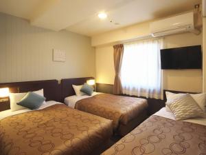 ein Hotelzimmer mit 2 Betten und einem Fenster in der Unterkunft Yokohama Heiwa Plaza Hotel in Yokohama