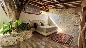a bedroom with a bed in a stone wall at Roots Tree House in Uluwatu