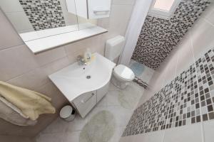 a white bathroom with a sink and a toilet at Apartments Mar - 150 m from sea in Rab