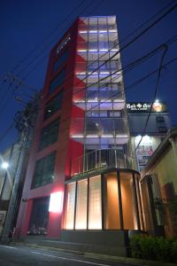 a tall red building with illuminated windows at night at ELE Cabin Shinjuku Kabukicho in Tokyo