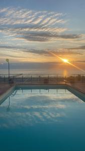 a swimming pool with the sunset in the background at Hotel Golden in Rimini