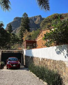 une voiture rouge garée dans un garage avec des montagnes en arrière-plan dans l'établissement Hospedaje Casa Teotleco, à Tepoztlán