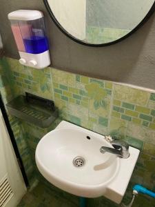 La salle de bains est pourvue d'un lavabo blanc et d'un miroir. dans l'établissement โรงแรมคุ้มเดช - KoomDech Hotel, à Sattahip