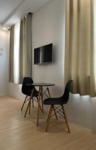 two chairs and a table with a television on a wall at Bambu Suites in Puerto Princesa City