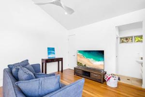 a living room with a blue couch and a tv at Ocean Blue @ Alex in Alexandra Headland