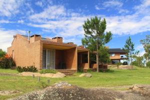 a brick house in a yard with a tree at Complejo Las Hoyas in Villa Carlos Paz