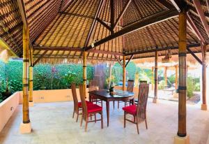 a dining room with a table and chairs under a pavilion at Giri's Villa Jimbaran in Jimbaran