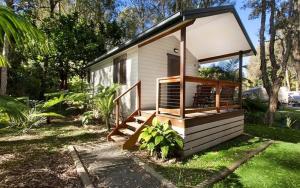 una pequeña casa con porche en un patio en Sapphire Beach Holiday Park, en Coffs Harbour