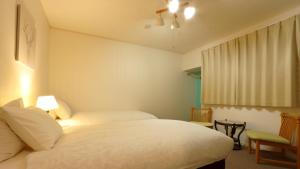 a bedroom with two beds and a window at Kusatsuonsen Ventvert in Kusatsu