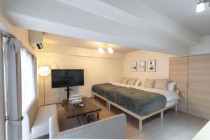 ein Schlafzimmer mit einem Bett, einem Fernseher und einer Couch in der Unterkunft Ocean Nipponbashi Higashi in Osaka
