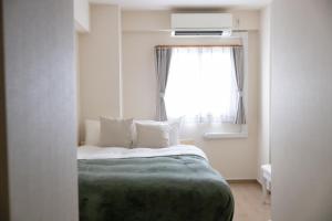 ein Schlafzimmer mit einem Bett und einem Fenster in der Unterkunft Ocean Nipponbashi Higashi in Osaka