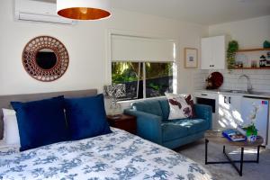 a bedroom with a blue bed and a blue couch at Private Beachside Studio with Courtyard and Sea view in Paraparaumu