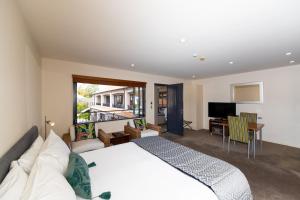 a bedroom with a white bed and a living room at Harvest Lodge Motel in Havelock North
