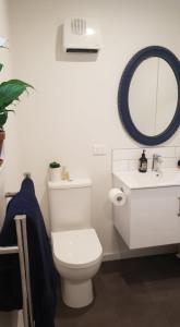 a white bathroom with a toilet and a sink at Private Beachside Studio with Courtyard and Sea view in Paraparaumu