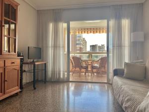Sala de estar con sofá, TV y mesa en Apartamento Atenas Piscina 4 pax, Inmobiliaria Leo Playa de San Juan, en Alicante