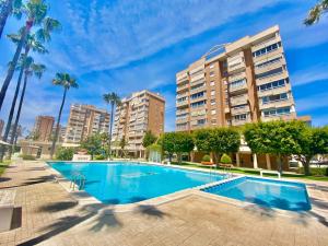 una piscina con palmeras y edificios en Apartamento Atenas Piscina 4 pax, Inmobiliaria Leo Playa de San Juan, en Alicante