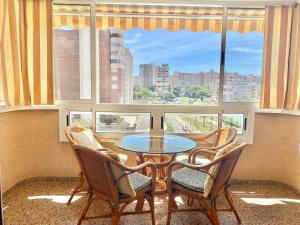 einen Tisch und Stühle in einem Zimmer mit Fenster in der Unterkunft Apartamento Atenas Piscina 4 pax, Inmobiliaria Leo Playa de San Juan in Alicante
